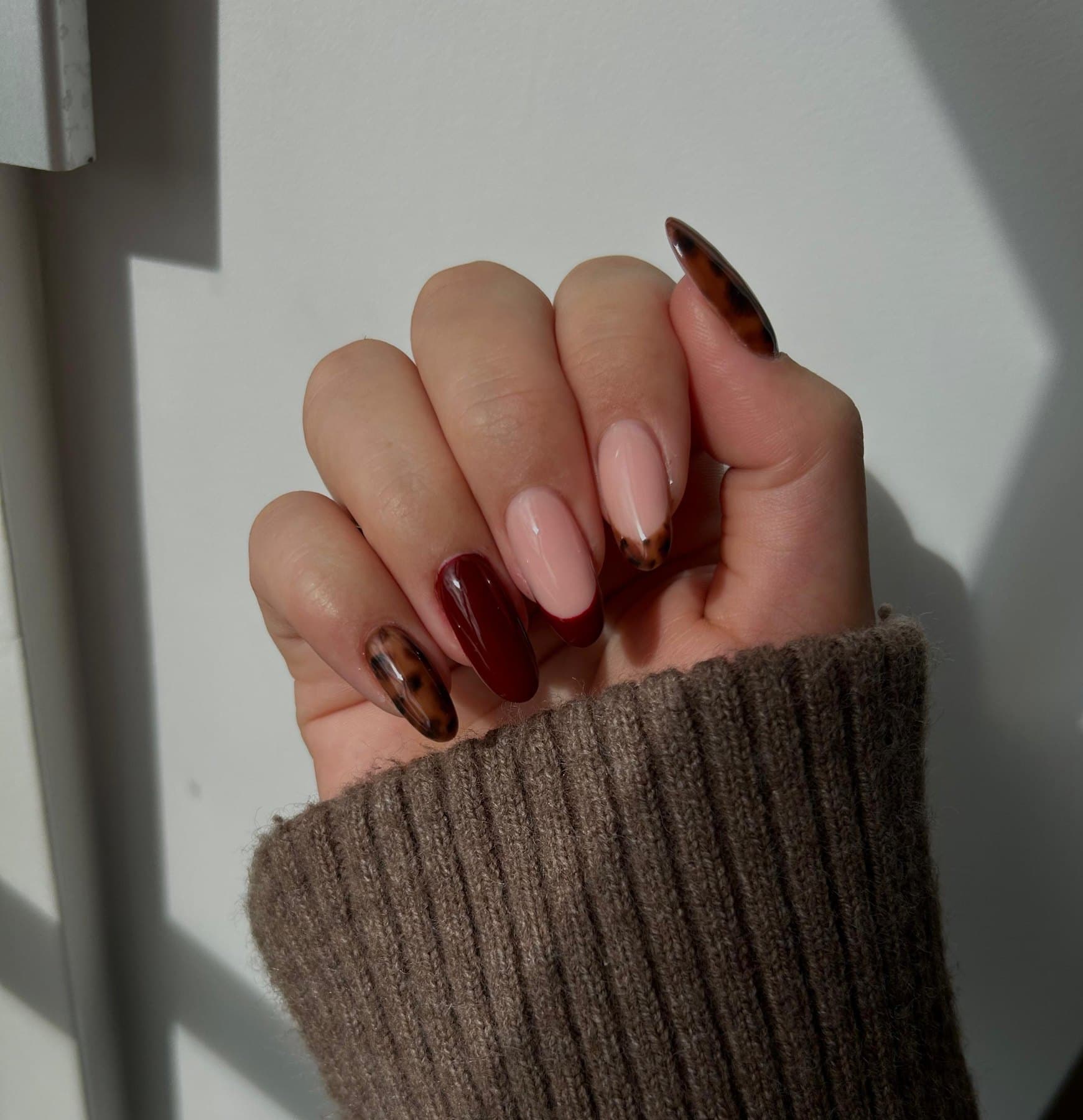 Nagels met een mix van bordeaux, nude en fijne nail art