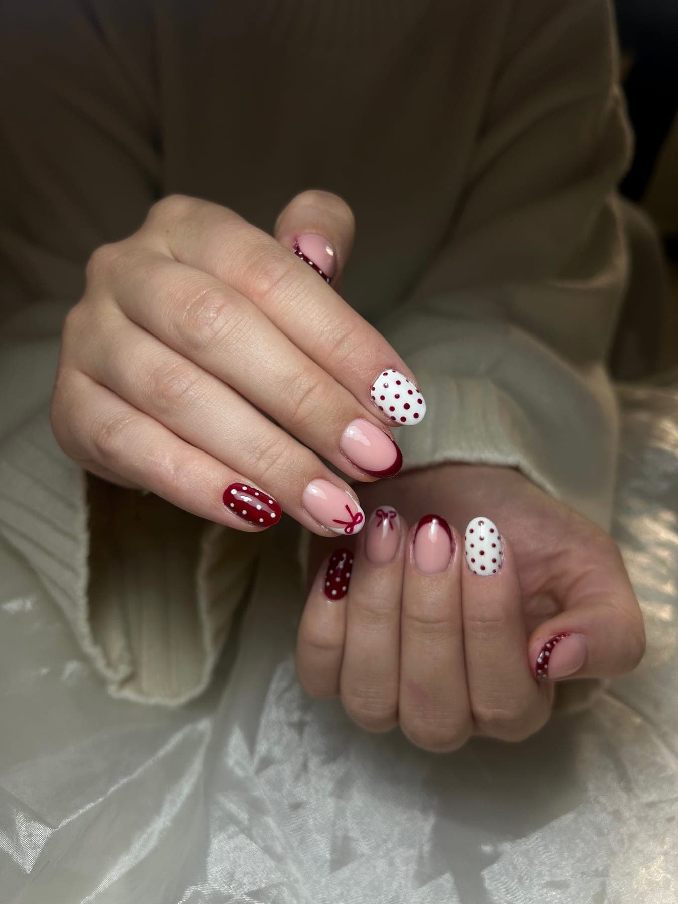 Nail art met bordeaux french, witte stippen en handgeschilderde strikjes — bekijk op Instagram